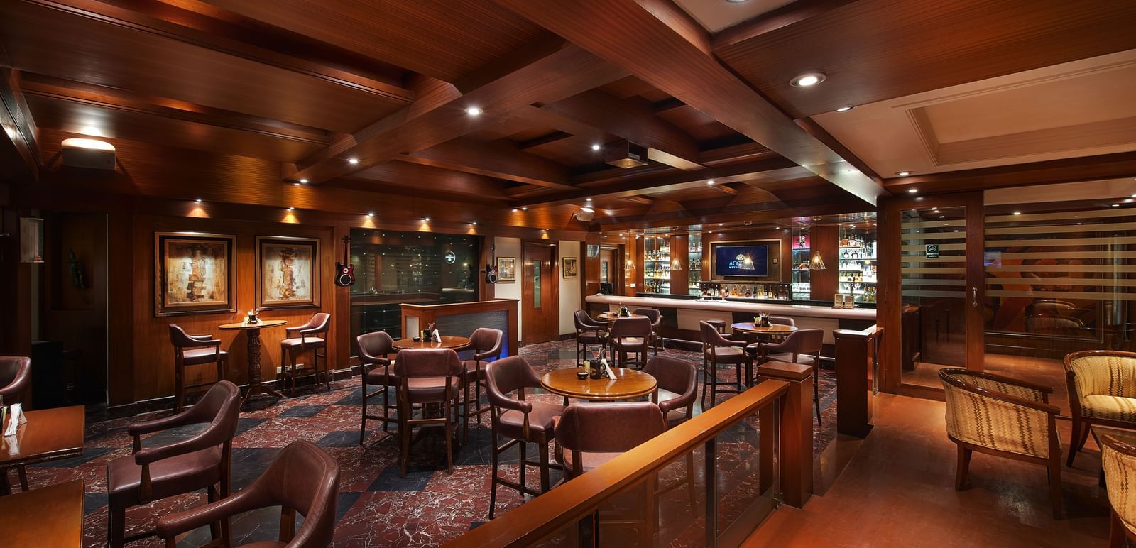 An image of a bar featuring many liquor products on the cabinets and shelves and a seating area with sofa chairs, chairs, and tables at Accord Hotels and Resorts